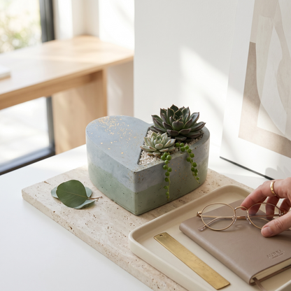 RAW & UNIQ heart-shaped concrete succulent planter in sage and grey with gold leaf accents on a travertine tray.